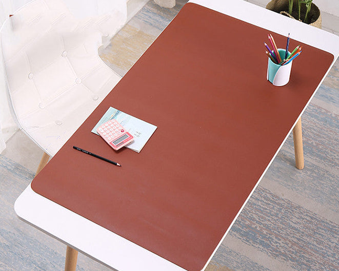 Brown desk mat on a white table with stationery items in a home office setting