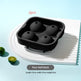 Black silicone four-ball ice mold tray shown on a white plate with two small green limes, on a light blue background. Red text reads '2pcs' and a gray label reads 'Four-ball black' with dimensions below.
