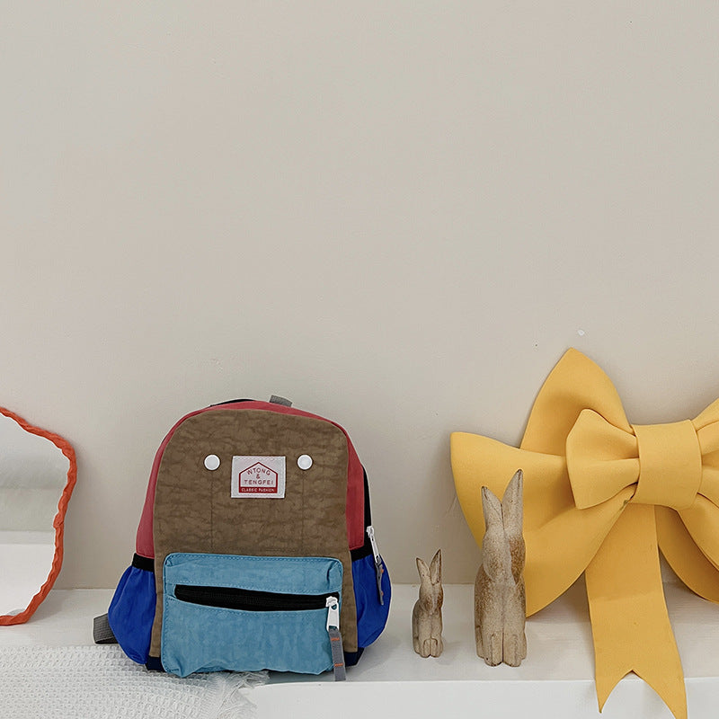 Children's backpack with a red and blue design on a white surface with decorative items.