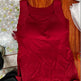 Red dress on a wooden hanger with a floral-patterned floor in the background