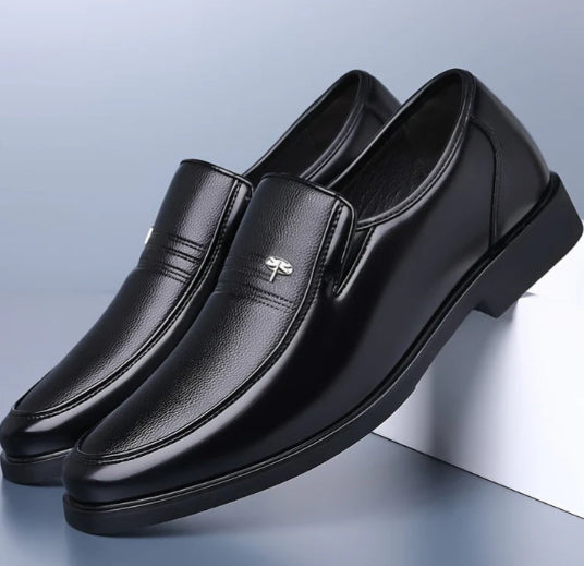 Pair of black leather loafers on a light blue background