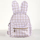 A small bunny-shaped backpack with long ears, featuring a beige and white gingham check pattern and a front zippered pocket with a gold zipper pull.