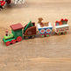 Wooden toy train set with Christmas-themed carriages on a wooden surface