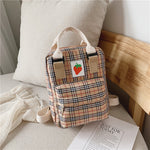 Plaid backpack with a strawberry sticker on a bed