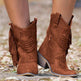 Brown fringe boots worn by a person on a blurred natural background