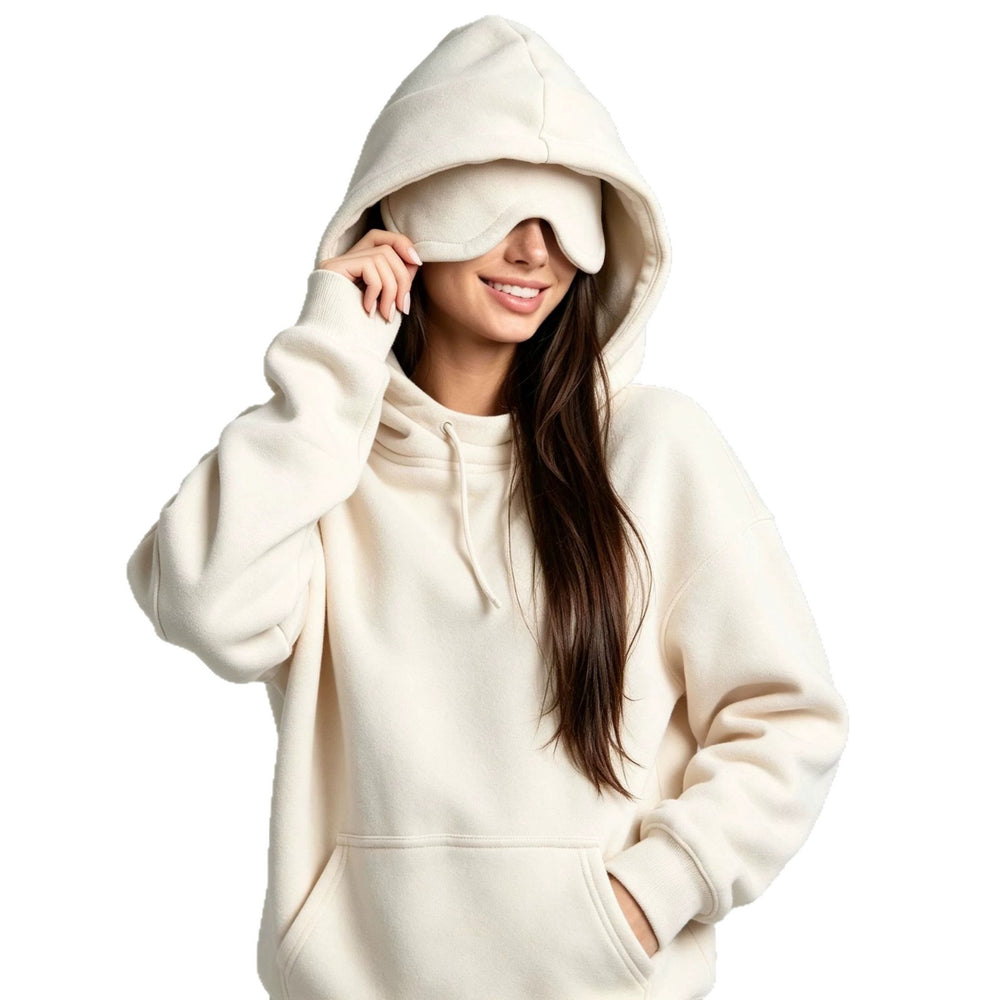 A woman wearing a cream-colored fleece hoodie and a matching eye mask, posing against a solid white background.