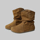Pair of brown suede boots on a white surface with a blurred background