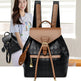 Black and brown backpack with a woman holding a smaller black bag in the background.