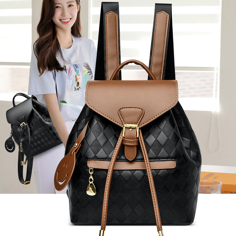 Black and brown backpack with a woman holding a smaller black bag in the background.