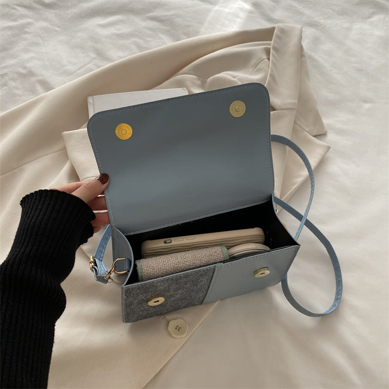 Gray handbag with gold buttons on a beige fabric background