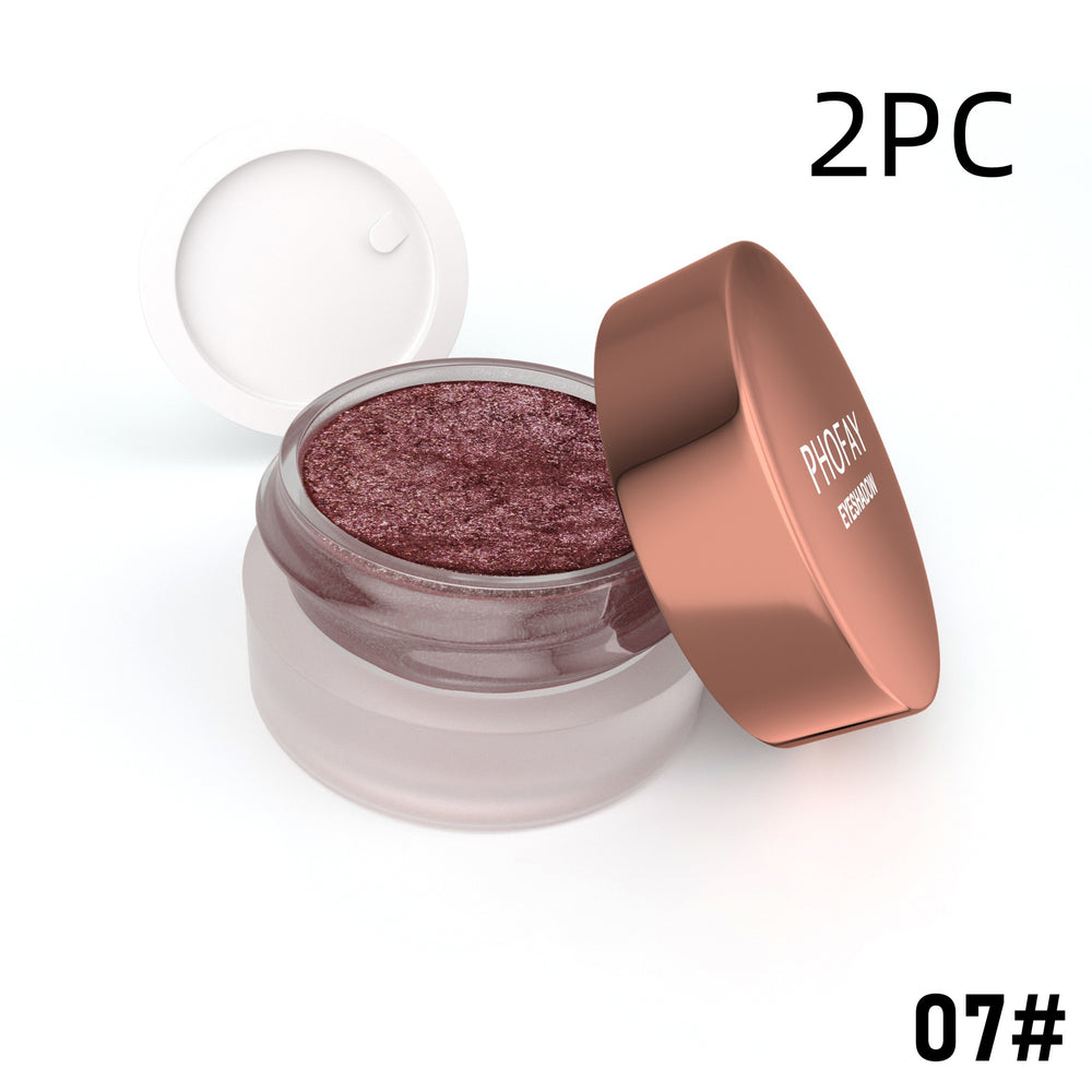 Open jar of glittery makeup with a rose gold lid on a white background