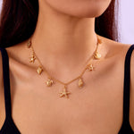 Gold necklace with starfish and shell charms on a model wearing a black top.