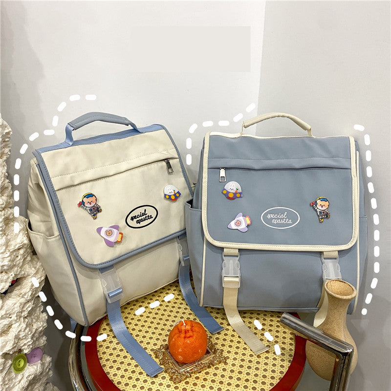 Two backpacks, one beige and one gray, with decorative elements on a textured surface.