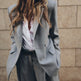 Person wearing a light gray coat against a beige wall.