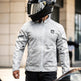 Person wearing a white motorcycle jacket with brand logos, standing outdoors.