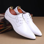 White dress shoes with black soles on a brown surface