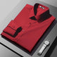 Folded red shirt with a white watch on a gray surface