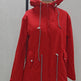 A bright red hooded parka jacket displayed on a dress form mannequin against a plain light gray wall. The jacket features a full front zipper, drawstring hood with white cord toggles, and zippered hand pockets.