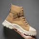 Tan tactical boot with white sole held against a gray background