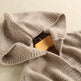 Close-up of a beige sweater with a mannequin head inside on a light beige background