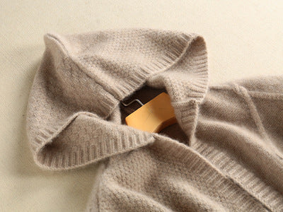 Close-up of a beige sweater with a mannequin head inside on a light beige background