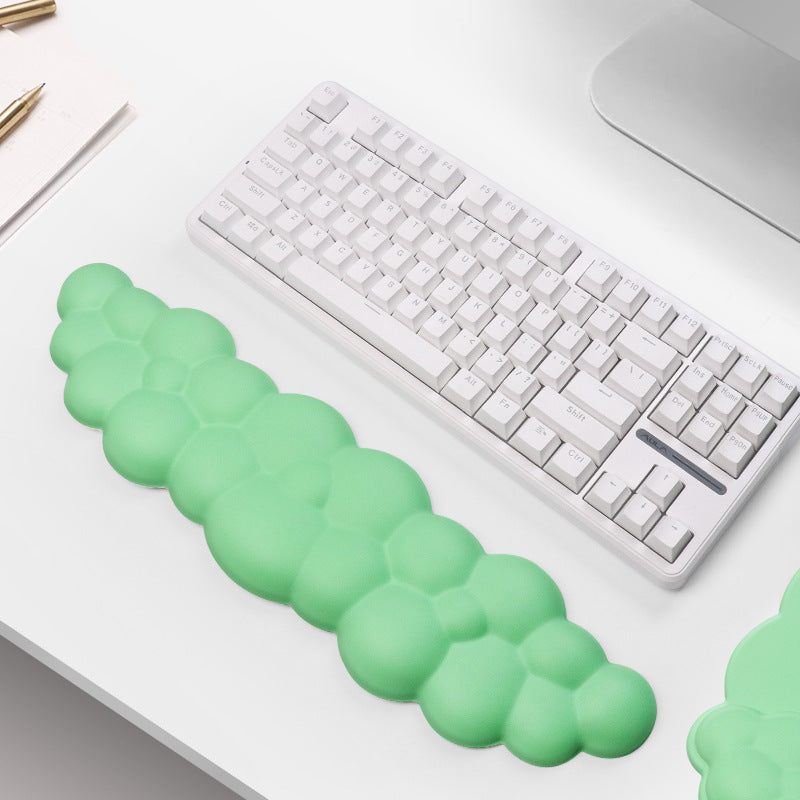 Green gel wrist pad on a keyboard with a laptop and pen in the background