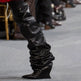 Black leather knee-high boots on a gray carpet
