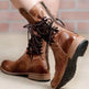 Brown leather boots with laces worn by a person on a light background