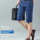 A man modeling dark blue denim knee-length shorts with a brown belt, paired with brown leather dress shoes and holding a black briefcase, set against a light gray studio background with promotional text.