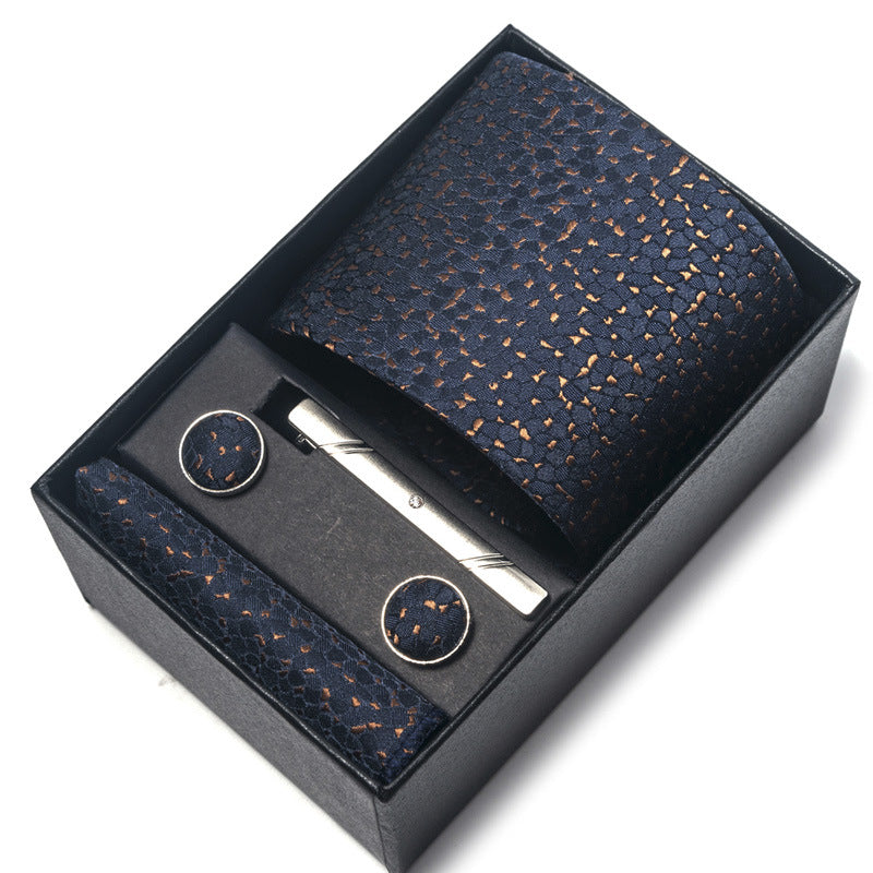Navy patterned tie set with tie clip and pocket square in a black box on a white background