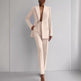 Person wearing a light pink suit against a gray background