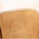 A close-up of a tan suede or microfiber cushion cover with a beige stitched edge, resting on a white faux fur surface.