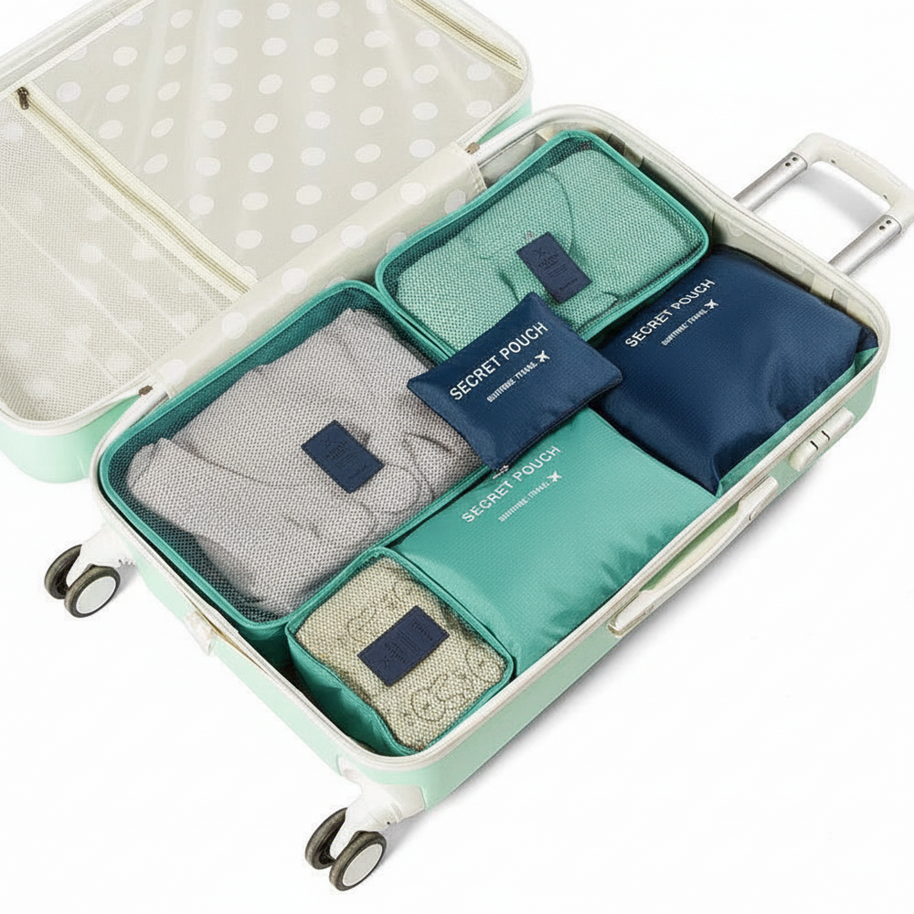 Ein mintgrüner Koffer geöffnet, um Packwürfel und Reisetaschen im Inneren zu zeigen. Das Set beinhaltet graue, türkisfarbene und marineblaue Stoff-Packwürfel mit marineblauen Etiketten, auf denen 'GEHEIME TASCHE' und 'GEHEIMER BEUTEL' steht.