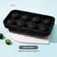 Two black silicone ice cube molds with eight spherical cavities each, displayed on a white curved riser against a light blue background with small lime slices and text overlays.
