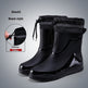 Black rain boots with pull beam feature on a gray background