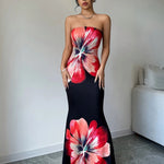 Woman wearing a strapless dress with large floral patterns in a minimal room.