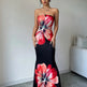 Woman wearing a strapless dress with large floral patterns in a minimal room.