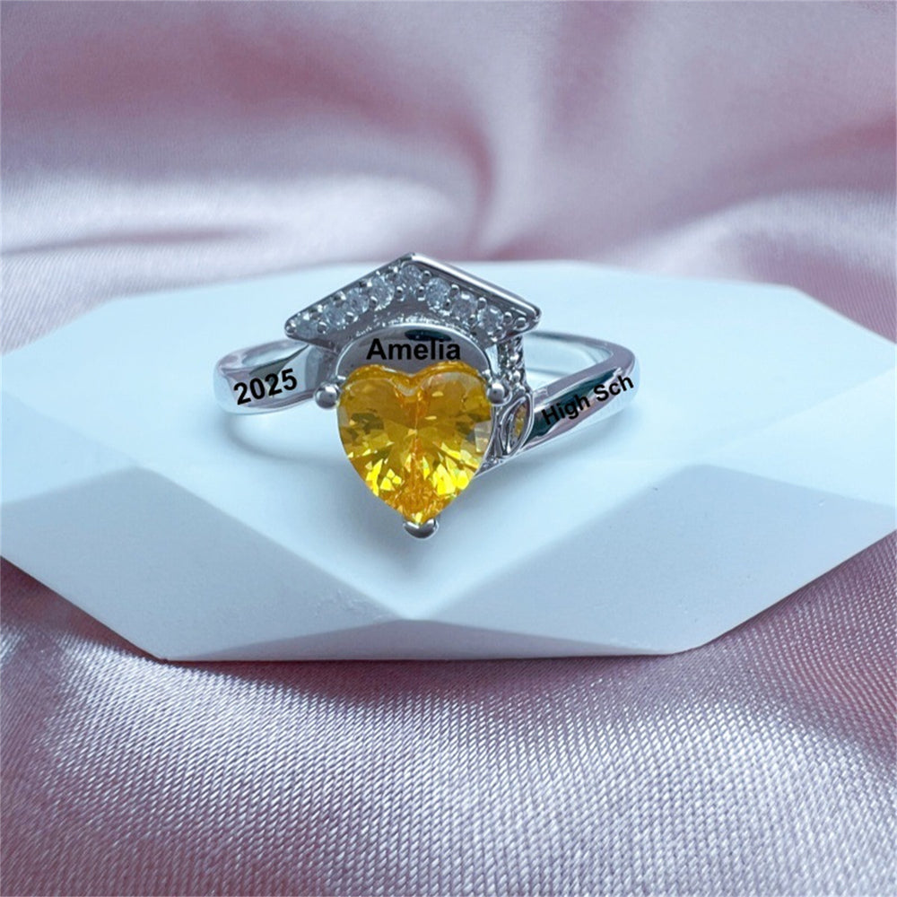 Ring with yellow gemstone and engraved text on a pink fabric background