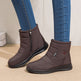 Brown winter boots with zippers worn with blue jeans on a beige surface.