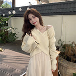 Woman in a light-colored outfit holding a book outdoors