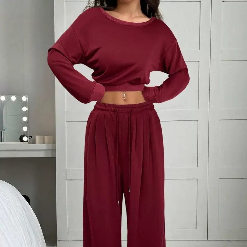 Person wearing a burgundy outfit in a room with a mirror and candles.