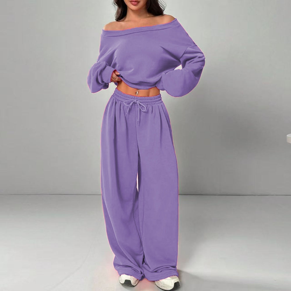 Person wearing a purple off-shoulder top and wide-leg pants on a gray background