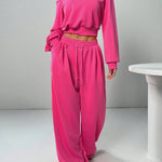 Person wearing a bright pink off-shoulder top and matching pants on a plain background