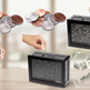 Two black coin-included savings boxes shown on a tabletop, with hands inserting coins and dollar bills flying out. Coins and hands are also shown at the top left against a softly blurred indoor background.