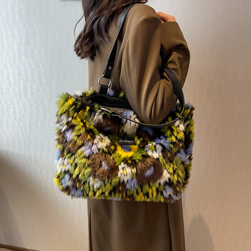 Person holding a colorful textured handbag against a neutral background