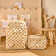 A beige and cream checkered backpack and matching zippered pouch with the name 'Ava' embroidered in white script, styled on a wooden floor in a nursery-like setting.