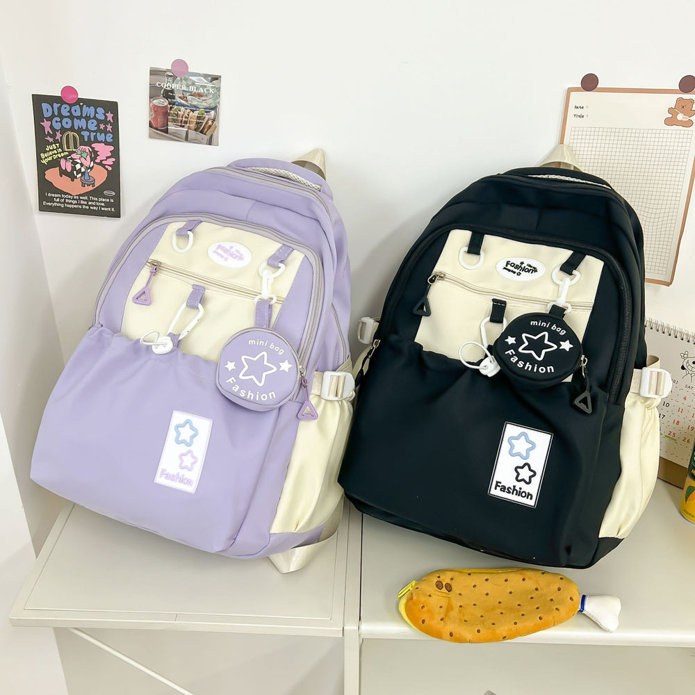 Two backpacks, one purple and one black, with visible brand logos on a white surface.