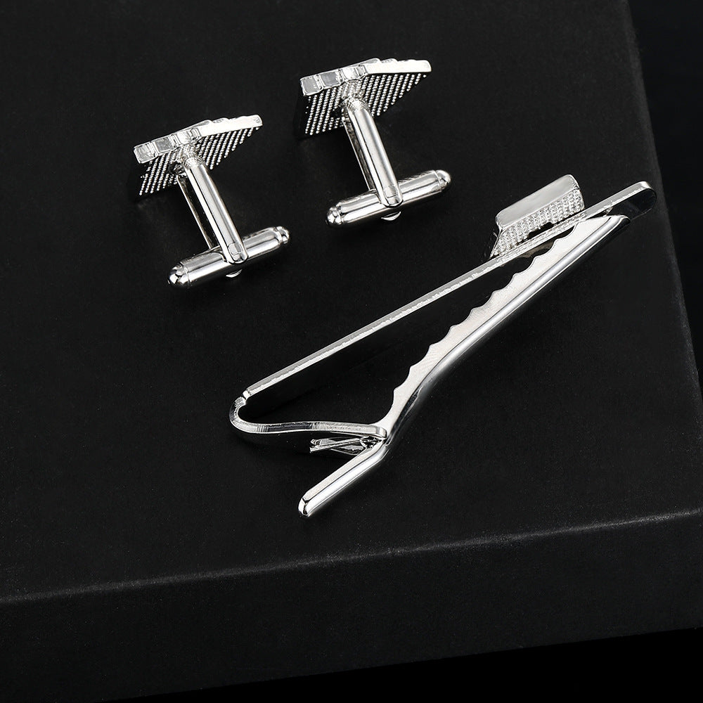 Silver cufflinks and tie clip on a black background