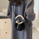Person wearing a gray coat with a black handbag featuring white fur trim.