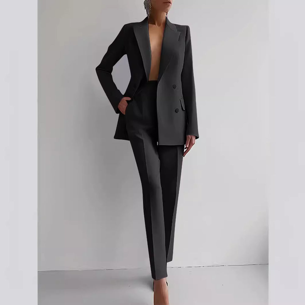 Person wearing a black suit against a plain background